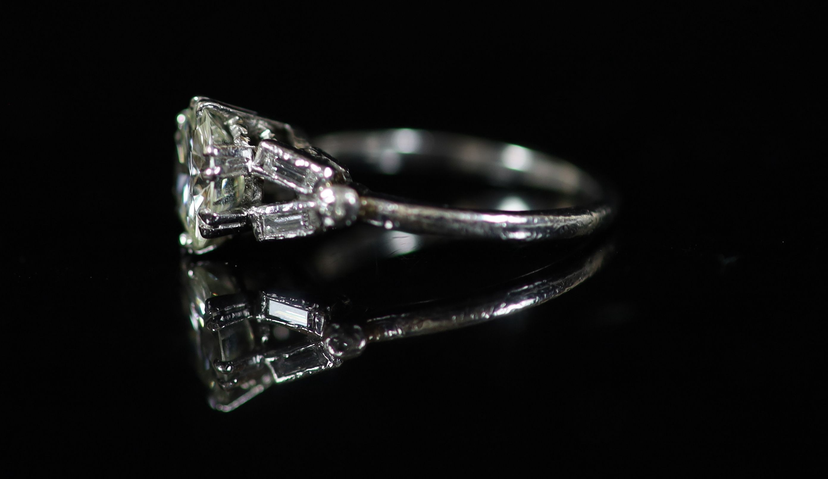 A platinum and single stone diamond ring, with baguette and diamond chip set shoulders